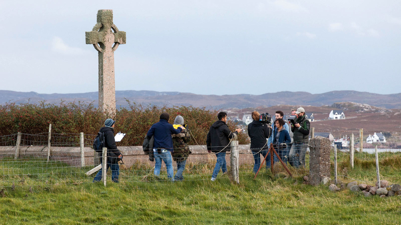Iona crew filming near a stone cross outdoors